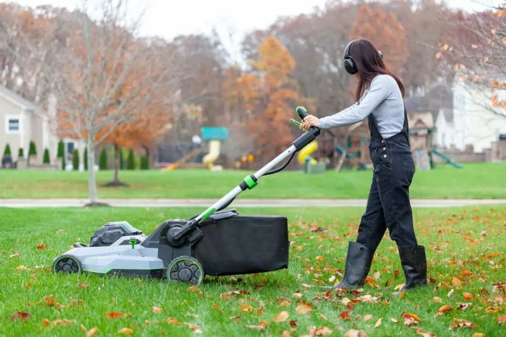 woman wearing noise blockers is operating a lawnmover