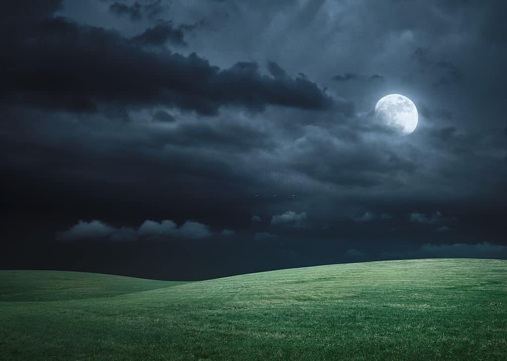 hilly meadow illuminated with moonlight