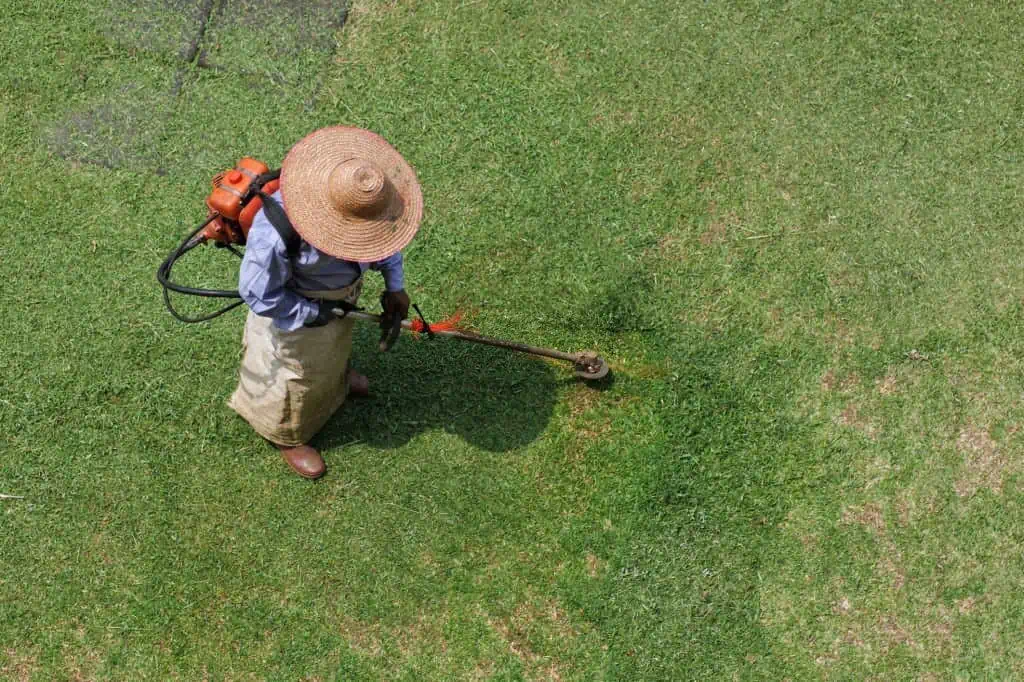 man mowing grass with string trimmer
